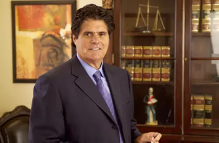 A man in suit and tie standing next to a book case.