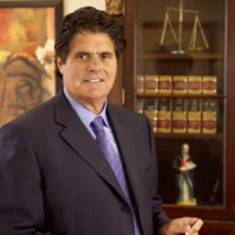 A man in suit and tie standing next to a book case.